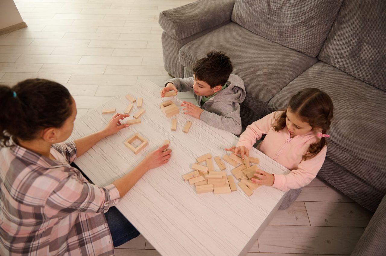 Une famille joue à un jeu de société en bois autour d’une table.